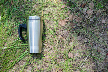 A steel tourist cup on the green grass background.