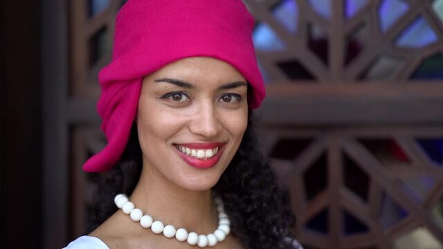 portrait of charming cuban or brazil woman with pink headscarf, smiling broadly
