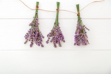 Fresh lavender flower bouquets are dried on rope on white wooden background. Flatlay herbal flower blossom. Lavender aromatherapy. Pink background. Rustic provence french style