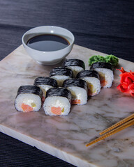 Sushi. A serving of fresh Japanese rolls on a marble board with soy sauce, wasabi and pickled ginger.
