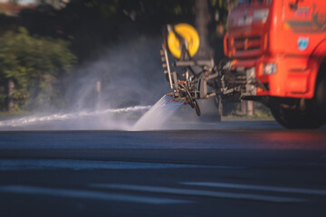 Cleaning flusher sweeper machines washes the city streets road with water spray, group of municipal watering machines wash asphalt, process of street disinfection and cleaning from dust and dirt