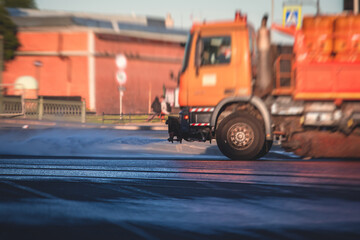 Cleaning flusher sweeper machines washes the city streets road with water spray, group of municipal...