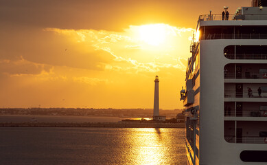 View at large cruise liner ship in port on sunset background with lighthouse. Copy space