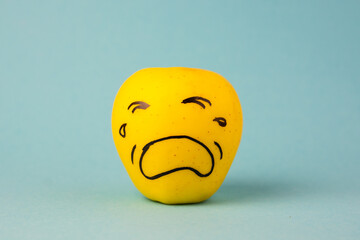 apples face with negative emotion on it, yellow background