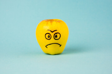 apples face with negative emotion on it, yellow background