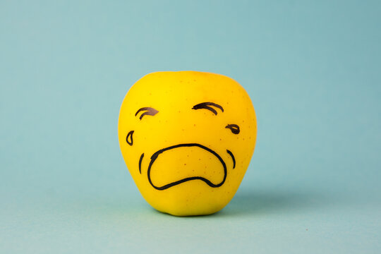 apples face with negative emotion on it, yellow background