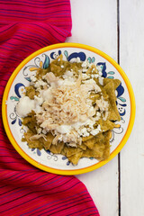 Mexican green chilaquiles with chicken and cheese on white background