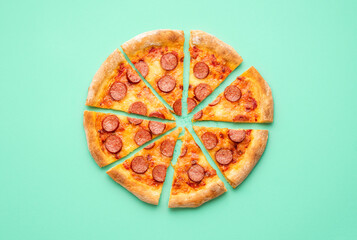 Pepperoni pizza flat lay on a green background. Sliced pizza isolated on a colored background