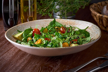 Nutritious low calorie organic vegetable salad made from green leaves and tomato and avocado seasoned with olive oil