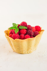 Homemade shortcrust raspberry pastry. Summer berries mini tartlets with vanilla custard and mint leaves. Fresh desserts on the white background isolated. Free copy space.