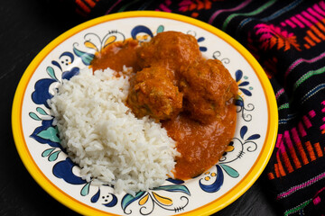 Mexican meatballs with chipotle sauce and rice on dark background