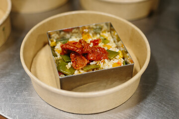 Preparing a rice salad in a mold to take away. The containers used are compostable.