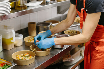 Cook preparing rice salads to take away. The containers used are compostable.
