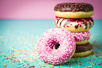 Multicolored sweet donuts with colourful decorations on colourful background.