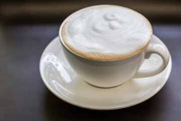 Foamy cappuccino coffee drink in white mug saucer