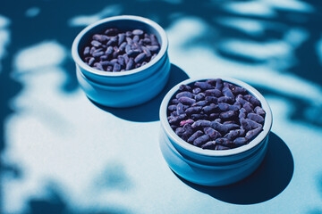 Obraz na płótnie Canvas Honeysuckle berries in a blue bowl on a blue background. Shadows. Harvest