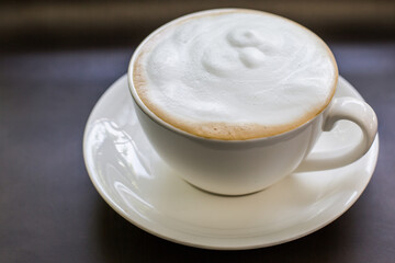 Foamy cappuccino coffee drink in white mug saucer