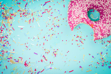 Fototapeta premium Pink sweet donut with colourful decorations on blue background.