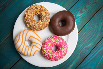 Sweet donuts, cakes on a white plate and a wooden table