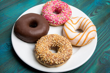 Sweet donuts, cakes on a white plate and a wooden table