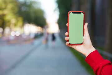green screen smartphone in red case with city background
