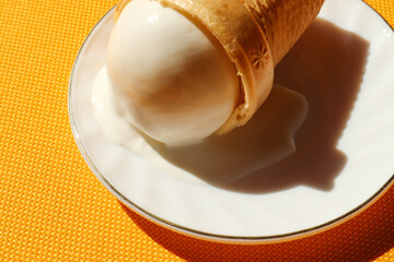 Melted cream ice cream on a white saucer close-up, side view, place for the inscription