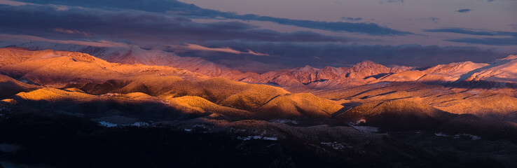 Unreal view with orange light of dawn over snowy mountains in the Pyrenees, Spain.
