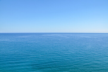 Calm deep sea with ripples on the surface and blue clear sky. Water natural background or texture 