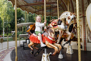 little girl on the carousel in the summer