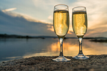Two glasses with champagne on the background of the sunset, in nature, outdoors. Ramontic evening for lovers