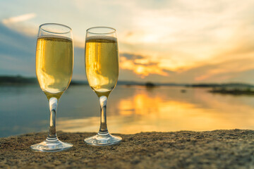 Two glasses with champagne on the background of the sunset, in nature, outdoors. Ramontic evening for lovers