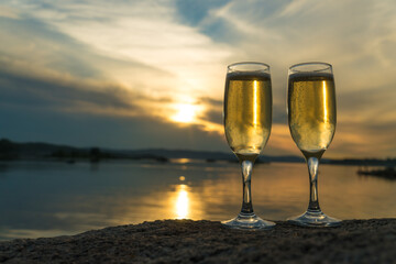 Two glasses with champagne on the background of the sunset, in nature, outdoors. Ramontic evening for lovers