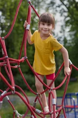 Fotobehang Adorable 6 years old  girl climbing the net in the playground © Albert Ziganshin