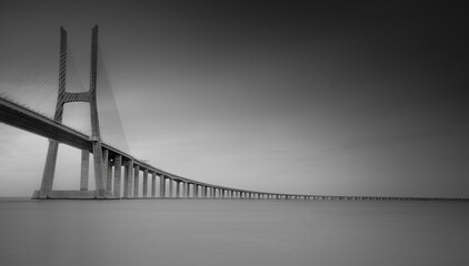 Vasco da Gama Bridge, the longest bridge in Europe, spans the Tagus River, in Lisbon, Portugal. Long exposure, black and white