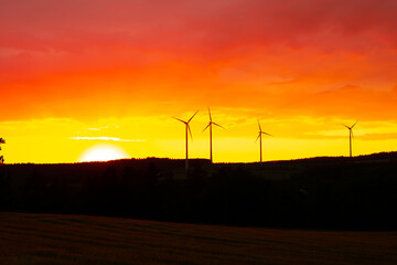 Fototapeta na wymiar Orange Sky Sunset with wind turbines silhouettes in the background