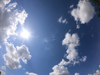 blue sky with white clouds and a bright sun