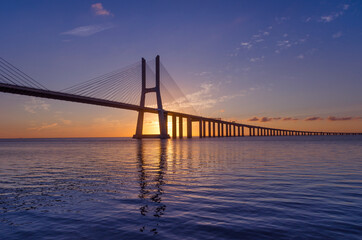 Fototapeta na wymiar Sunrise at Vasco da Gama Bridge, the longest bridge in Europe, who spans the Tagus River, in Lisbon, Portugal.