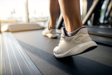 Close-up of athletic woman exercising on treadmill in a gym.