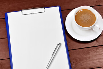 Clipboard with pen and coffee cup on a wooden table
