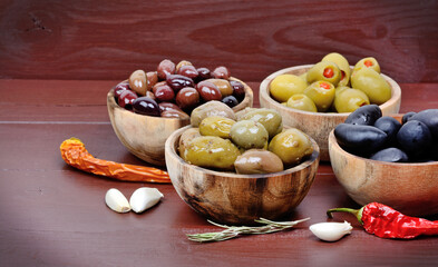 Different types of olives in a wooden bowls