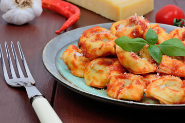 Tortellini with tomatoes sauce and parmesan in a plate