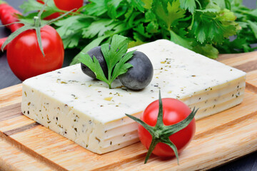 Herbs cheese with olives, cherry tomatoes and parsley on a wood cutting board