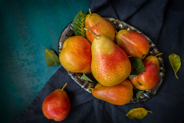 Ripe pears on a plate on a blue-green background close-up.