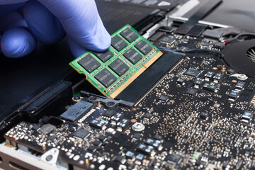 Service engineer install new RAM memory chips to the laptop. Repairing and upgrading laptop...
