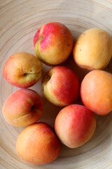 Wooden bowl with fresh organic apricots on the table. Top view.