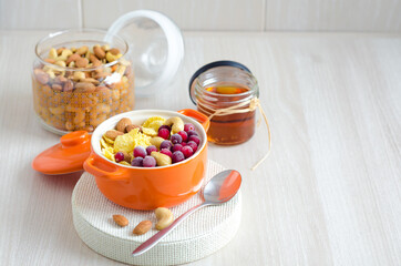 cornflakes, nuts, berries, honey for healthy and nutritious breakfast on light background with copy space, place for text.