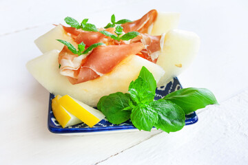  Grube plastry soczystego, słodkiego melona z szynką prosciutto ozdobione listkami mięty © Monika