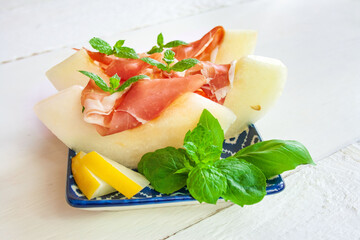 rube plastry soczystego, słodkiego melona z szynką prosciutto ozdobione listkami mięty © Monika