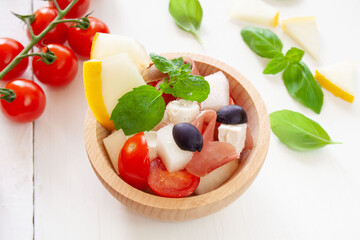 Salad with Parma ham, melon, cherry tomatoes, feta cheese and olives, decorated with mint and basil leaves