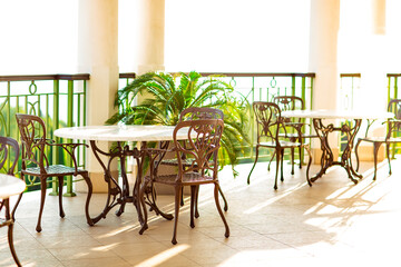 outdoor summer terrace, with cast iron.stylish furniture, in a cafe at sunset